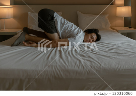 Man resting on the hotel bed as he tired from traveling. 120310060