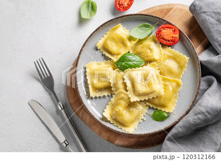 Homemade ravioli pasta with cheese, tomatoes and basil in a plate on a wooden board  120312166