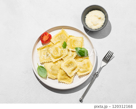 Ravioli pasta with parmesan, tomatoes and basil in a plate on a light background with shadow Ravioli pasta with parmesan, tomatoes and basil in a plate on a light background with shadow 120312168