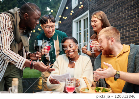 Vibrant shot of multiethnic group of adult friends looking at ultrasound image of Black young woman announcing pregnancy at party outdoors Vibrant shot of multiethnic group of adult friends looking at ultrasound image of Black young woman announcing pregnancy at party outdoors 120312846