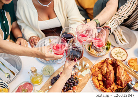 Top view group of adult friends clinking wine glasses and enjoying drinks over dinner table celebrating holidays together copy space Top view group of adult friends clinking wine glasses and enjoying drinks over dinner table celebrating holidays together copy space 120312847