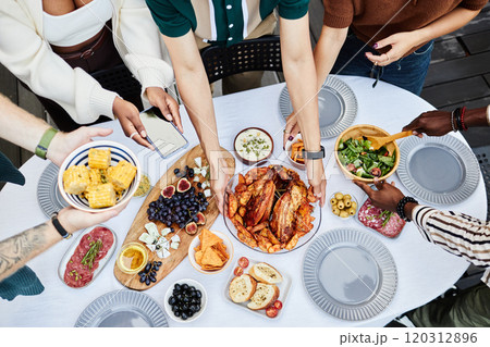 Top view closeup of people setting dining table together with hands serving dishes shot with flash copy space 120312896