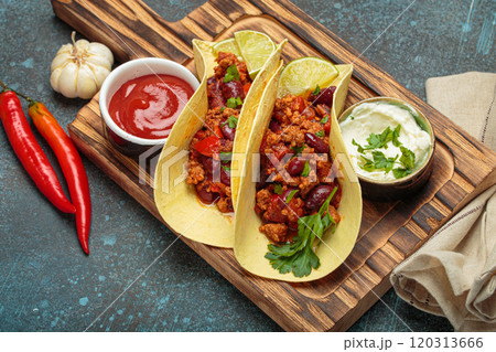 Mexican tacos with chili con carne, red beans, and lime wedges on wooden board top view Mexican tacos with chili con carne, red beans, and lime wedges on wooden board top view 120313666