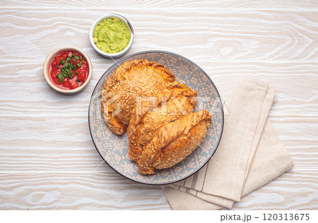 Delicious baked empanadas with sesame seeds in a bowl with sauces, traditional Spanish savoury pastry 120313675