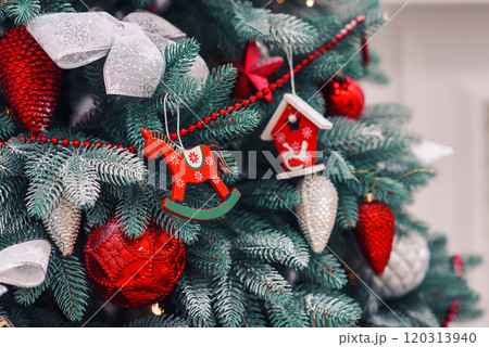 Close up of red decorations on artificial green Christmas tree with snow. 120313940