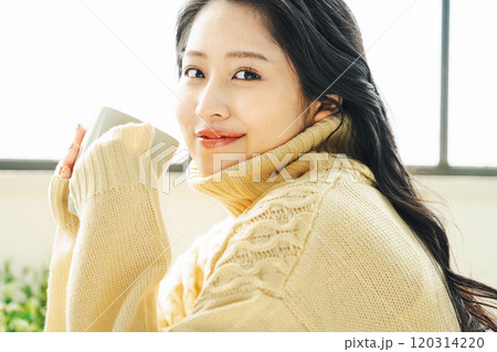 コーヒーを飲む冬服の若い女性 120314220