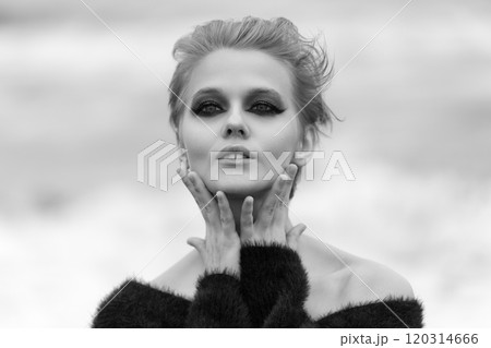 Woman with short hair and makeup is striking pose on natural background. Fashion model playfully put both palms on neck, looks so confident and looking at camera. Black and white dramatic portrait Woman with short hair and makeup is striking pose on natural background. Fashion model playfully put both palms on neck, looks so confident and looking at camera. Black and white dramatic portrait 120314666