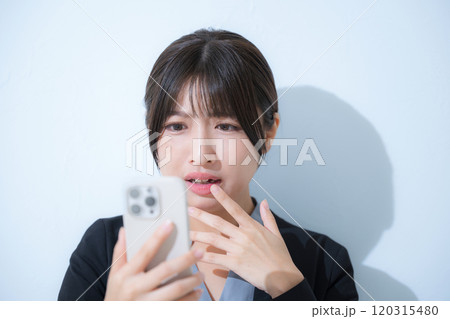 スーツを着てスマホを見る驚く女性のクローズアップのビジネスシーン スーツを着てスマホを見る驚く女性のクローズアップのビジネスシーン 120315480