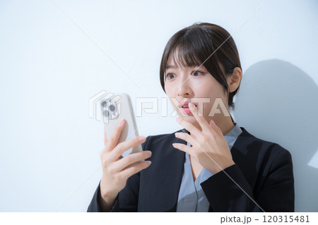 スーツを着てスマホを見て驚く女性のクローズアップのビジネスシーン 120315481
