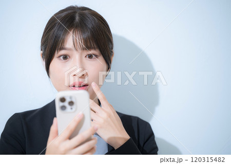 スーツを着てスマホを見て驚く女性のクローズアップのビジネスシーン 120315482