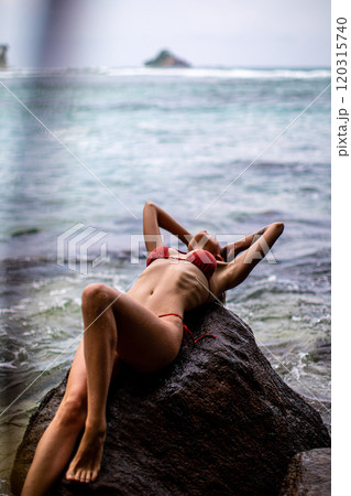 A Relaxing Woman in a Bikini Enjoying Her Time by the Beautiful Beach and Ocean Waves 120315740