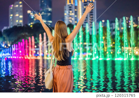 Woman tourist on background of colorful fountain on the lake at night, near by Twin Towers with city on background. Kuala Lumpur, Malaysia 120315765