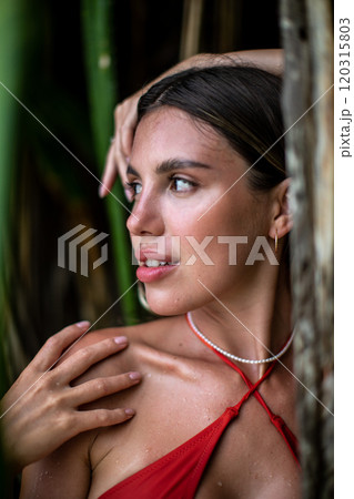 A Cheerful Smiling Woman Wearing an Orange Bikini Surrounded by Lush Greenery and Nature 120315803