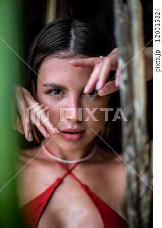 A Cheerful Smiling Woman Wearing an Orange Bikini Surrounded by Lush Greenery and Nature 120315824