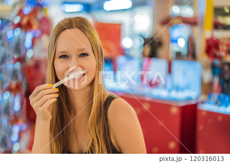 A woman with paper strips in her hands listens to the fragrance in the mall 120316013
