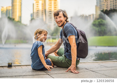 Dad and son tourists on background of fountain on the lake at night, near by Twin Towers with city on background. Kuala Lumpur, Malaysia 120316058
