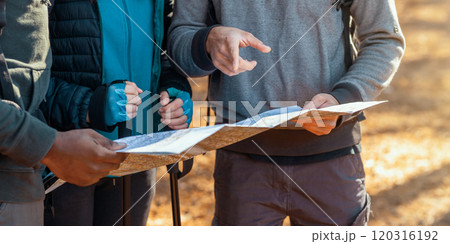 Cropped of multiracial friends with backpacks looking at map, hiking in autumn forest 120316192