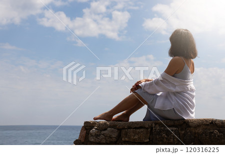 Woman sitting on a rock by the sea 120316225