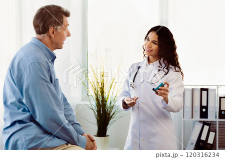 Healthcare Concept. Mexican doctor explaining how to use asthma inhaler to senior patient, empty space 120316234