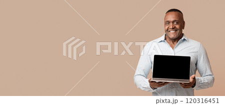Useful website. Middle aged afro man showing laptop with blank screen, orange studio background 120316451