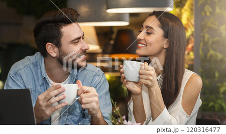 Dating. Young couple tasting coffee drinks enjoying flirt and conversation during weekend date sitting in cozy cafe 120316477