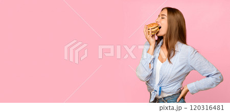 Cheat meal. Hungry millennial girl eating burger enjoying unhealthy fast food standing on yellow studio background. Panorama, empty space Cheat meal. Hungry millennial girl eating burger enjoying unhealthy fast food standing on yellow studio background. Panorama, empty space 120316481