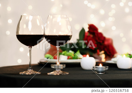 Romantic Evening. Affectionate couple dating in restaurant, two glasses with red wine in foreground, selective focus Romantic Evening. Affectionate couple dating in restaurant, two glasses with red wine in foreground, selective focus 120316758