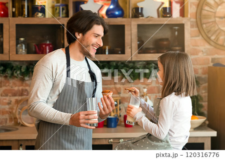 Snack Time. Cheerful Father And Daughter Eating Biscuits And Drinking Milk In Kitchen Together, Chatting And Laughing, Free Space Snack Time. Cheerful Father And Daughter Eating Biscuits And Drinking Milk In Kitchen Together, Chatting And Laughing, Free Space 120316776