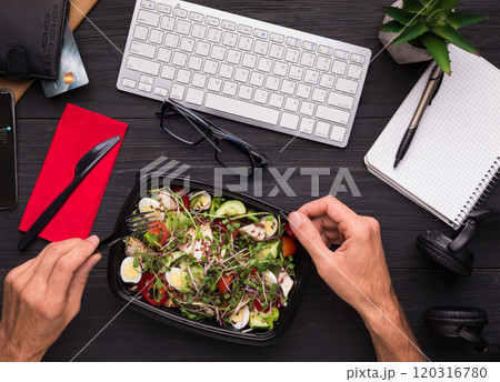 Having lunch at workplace. Businessman enjoying healthy salad at work desk, top view 120316780