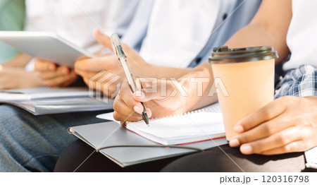 Unrecognizable Student Girl Writing Essay Outdoors, Preparing For Classes With Her College Friends Together, Cropped Image, Closeup Unrecognizable Student Girl Writing Essay Outdoors, Preparing For Classes With Her College Friends Together, Cropped Image, Closeup 120316798
