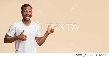 Excited Afro Guy Pointing Fingers Aside With Both Hands Standing On Yellow Studio Background. Panorama, Copy Space Excited Afro Guy Pointing Fingers Aside With Both Hands Standing On Yellow Studio Background. Panorama, Copy Space 120316843