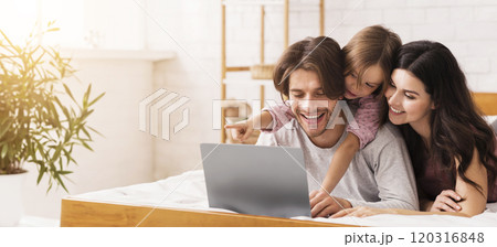 Lazy Family Weekend. Happy Parents And Cute Little Daughter Using Laptop In Bed, Downloading Movies To Watch, Browsing Internet 120316848