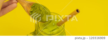 Green tea latte with ice in mason jar and straw and spoon with powder matcha on yellow background. Homemade Iced Matcha Latte Tea with Milk zero waste BANNER, LONG FORMAT 120316909