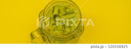 Green tea latte with ice in mason jar and straw on yellow background. Homemade Iced Matcha Latte Tea with Milk zero waste BANNER, LONG FORMAT Green tea latte with ice in mason jar and straw on yellow background. Homemade Iced Matcha Latte Tea with Milk zero waste BANNER, LONG FORMAT 120316925