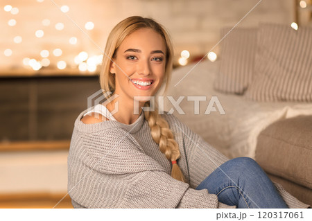 Happy millennial couple sitting in front of Christmas tree, smiling to camera, free space 120317061