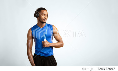 Fitness Model. Confident afro man wearing headphones and holding jumping rope on neck over yellow studio wall, copyspace Fitness Model. Confident afro man wearing headphones and holding jumping rope on neck over yellow studio wall, copyspace 120317097