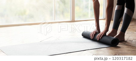 Cropped photo of girl getting ready before morning yoga practice, placing her yoga mat on floor at fitness studio, panorama with copy space Cropped photo of girl getting ready before morning yoga practice, placing her yoga mat on floor at fitness studio, panorama with copy space 120317182