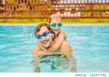 Dad and son in swimming Goggles have fun in the pool 120317192