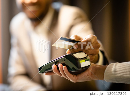NFC Technology. Close up of black manager smiling, giving credit card to waitress paying with gold credit card in cafe NFC Technology. Close up of black manager smiling, giving credit card to waitress paying with gold credit card in cafe 120317293