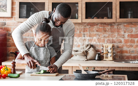 Cheerful African Man Showing His Lovely Daughter How To Cut Cucumber, cooking together at kitchen, copy space Cheerful African Man Showing His Lovely Daughter How To Cut Cucumber, cooking together at kitchen, copy space 120317328