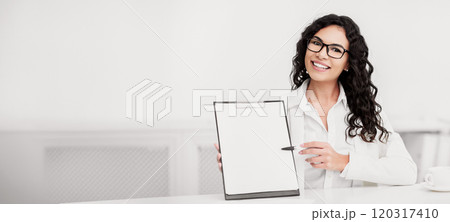 Mexican Businesswoman Showing Blank Clipboard, Pointing At Copy Space With Pen Mexican Businesswoman Showing Blank Clipboard, Pointing At Copy Space With Pen 120317410