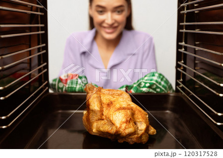 View from inside on delicious roasted chicken in oven and looking at it housewife View from inside on delicious roasted chicken in oven and looking at it housewife 120317528