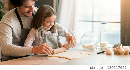 Home bakery. Loving dad showing to his little daughter how to roll the dough while preparing pastry in kitchen together, free space Home bakery. Loving dad showing to his little daughter how to roll the dough while preparing pastry in kitchen together, free space 120317631