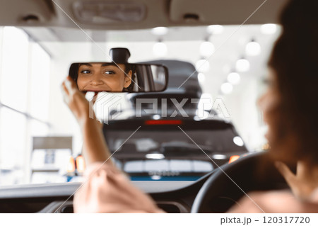 New Car Concept. Happy Afro Girl Checking Mirrors Sitting In Driver's Seat Testing Buying Auto In Dealership Store. Selective Focus New Car Concept. Happy Afro Girl Checking Mirrors Sitting In Driver's Seat Testing Buying Auto In Dealership Store. Selective Focus 120317720