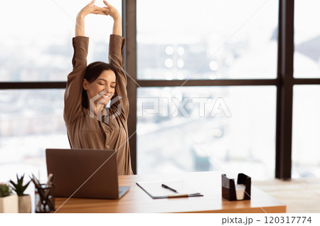 Good Morning. Happy female manager stretching her body and arms working at home or modern office, copyspace 120317774