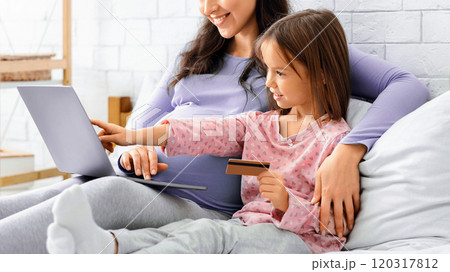 Online shopping. Pregnant mother and daughter making purchases online, using laptop in bedroom 120317812