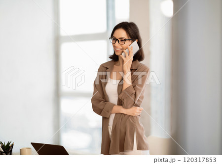 Calling Family. Portrait of happy girl in brown shirt making phone call to her relatives or friends, looking away Calling Family. Portrait of happy girl in brown shirt making phone call to her relatives or friends, looking away 120317853