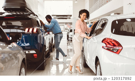 Couple Buying Car. African Spouses Choosing New Family Automobile In Luxury Dealership Store. Panorama 120317892