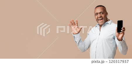 Music app. Positive mature african man in headphones enjoying music online, showing blank cellphone with mobile application 120317937