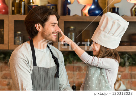 Baking Fun. Happy Little Girl And Her Dad Fooling Together While Cooking In Kitchen, Preparing Homemade Pastry, Cute Daughter In Chef's Hat Playfully Touching Father's Nose, Copy Space Baking Fun. Happy Little Girl And Her Dad Fooling Together While Cooking In Kitchen, Preparing Homemade Pastry, Cute Daughter In Chef's Hat Playfully Touching Father's Nose, Copy Space 120318028